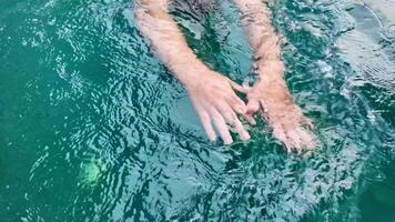 Close up of a Caucasian persons hands gently floating on calm turquoise water, conveying relaxation and leisure, related to summer vacations and World Oceans Day video