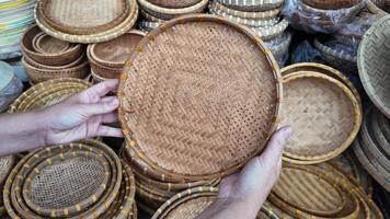 Close up of hands holding a woven bamboo basket among a collection of handmade baskets, ideal for handicraft, sustainable goods, and cultural markets concepts video