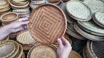 Person examining handmade woven rattan baskets at a traditional crafts market, suitable for topics on sustainable living and cultural festivals video