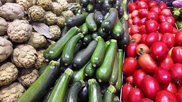 fresco orgânico abobrinha, alcachofras, e tomates em exibição às uma agricultores mercado, ideal para vegetariano receitas e Ação de graças lado pratos video