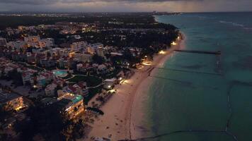 A stunning drone-captured aerial view reveals a coastal city at dusk, with sparkling city lights creating a mesmerizing scene. This tourist city is located in Punta Cana, Dominican Republic video