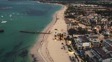 volo al di sopra di il spiaggia di un' popolare turista costiero città a crepuscolo. il città sotto scintille con luci, la creazione di un' travolgente spettacolo. punta cana, domenicano repubblica video