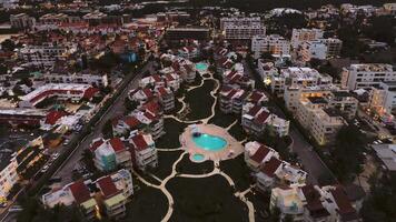 un aéreo crepúsculo ver de un popular costero turista ciudad, presentando un lujoso hotel con un iluminado piscina en medio de fascinante ciudad luces abajo. esta es punta cana, dominicano república video