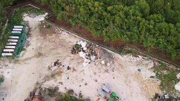 aérien vue de environnement crise dans le jungle - montrant des ordures décharge, pollution, abandonné machinerie, et écologique dommage. drone caméra descend tandis que capturer le scène de au-dessus de. video