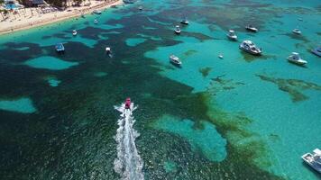 Antenne Aussicht von schnell Schnellboot ist Segeln durch schön Türkis Wasser mit ein Koralle Riff zwischen Weiß Yachten. luxuriös tropisch Karibik Küste. das Kamera folgt es video