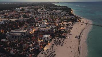 ipnotizzante fuco cattura costiero città a crepuscolo, offerta mozzafiato aereo prospettiva. scintillante città luci sotto creare sbalorditivo scena nel Questo turista punto di accesso situato nel punta cana, domenicano video