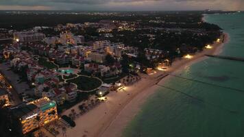 Stunning drone shot reveals coastal city at dusk, showcasing its sparkling city lights and creating mesmerizing scene. This tourist city is located in Dominican Republic, specifically in Punta Cana video
