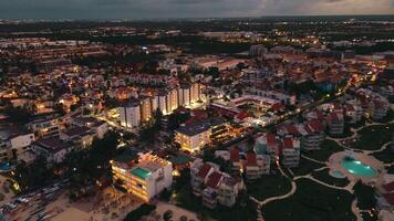 Stunning aerial view, taken with drone, reveals coastal city at dusk. The city below is aglow with sparkling lights, crafting captivating sight. This popular tourist destination. Punta Cana, Dominican video