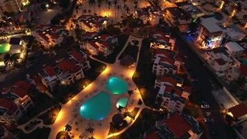 aéreo ver de popular turista costero noche ciudad. un lujoso turista hotel con un iluminado piscina. el espumoso ciudad luces abajo crear un fascinante fotografía. punta cana, dominicano república video