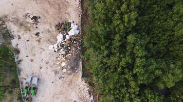 aéreo ver de ambiental crisis en el selva - demostración basura vertedero, contaminación, abandonado maquinaria, y ecológico daño. zumbido cámara desciende mientras capturar el escena desde arriba. video