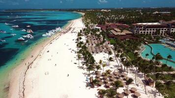 aérien vue de tropical plage de une luxe recours avec blanc le sable sur une brillant ensoleillé journée. paume des arbres, le Caraïbes mer, et une bassin. punta Cana, dominicain république video