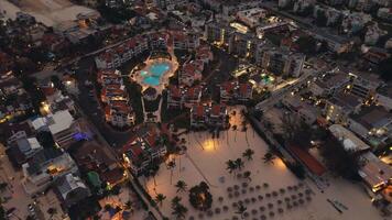 Stunning aerial view, captured by drone, showcases coastal city at dusk. City below is aglow with sparkling lights, creating captivating sight. This popular tourist destination Punta Cana, Dominican video