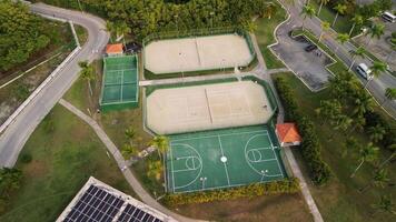 un aéreo ver de Deportes comodidades exhibiendo baloncesto y tenis tribunales, con personas activamente participativo en un enérgico tenis fósforo. esta escena es conjunto a misterios real playa punta cana hotel video