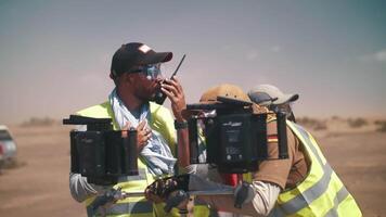 de direktör på de uppsättning av en filma i de öken- sänder något på de radio. filma besättning, sandstorm video