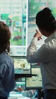 Vertical Diverse team following city traffic on a display in monitoring room, reviewing CCTV satellite radar footage. Employees working on surveillance and data collecting, control center. Camera A. video