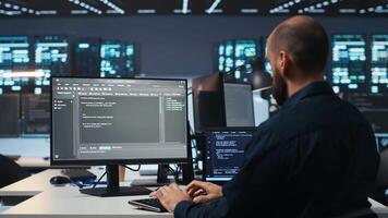 Entwickler Tippen Code, Arbeiten im Netzwerk Sicherheit Daten Center Einrichtung, gewährleisten optimal Leistung. es Fachmann mit Desktop pc zu Monitor Energie Verbrauch über Klinge Server Cluster video