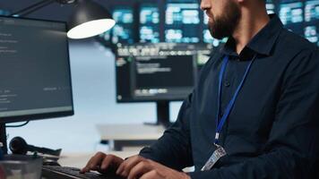 Technician coding in high tech facility with server rows providing computing resources for different workloads. Close up shot of worker overseeing supercomputers operating data video