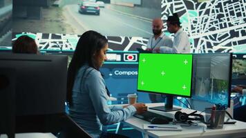 Indian employee follows order shipment next to a greenscreen on pc, communicating gps coordinates on satellite map for courier trying to avoid traffic. Cargo delivery agency. Camera B. video