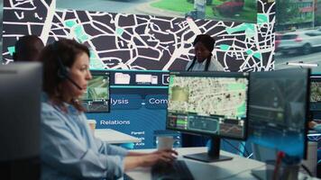 Diverse operators giving updates on order tracking to clients, working with surveillance CCTV footage in the CCTV and satellite map to ensure fast delivery. Employees in control center. Camera B. video