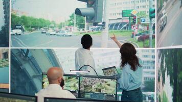 Diverse employees monitoring traffic via radar cameras at stop lights, using surveillance CCTV footage sensors in the city. People tracking cars in the government database, public safety. Camera B. video