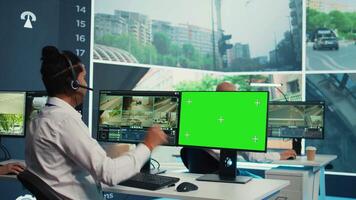 Indian operator monitors traffic next to a greenscreen on display, following surveillance footage from satellite radar cameras. Agency employee works with city CCTV system. Camera B. video