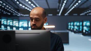 homem dentro servidor quarto digitando código, garantindo dados permanece blindado a partir de ameaças. panning tiro do isto técnico protegendo supercomputadores contra não autorizado acesso, protegendo sistema a partir de hackers video