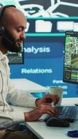 Vertical Middle eastern call center operator gives directions to the courier, avoid traffic by monitoring radar CCTV surveillance and a satellite city map. Employee helps with express delivery. Camera A. video