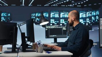 Man programming in high tech facility with server rows providing computing resources for different workloads. Admin reviewing data center supercomputers tasked with solving complex operations video