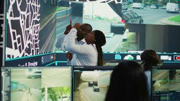 africano americano equipe monitoramento rotas e instruções em satélite mapa, guiando Entrega caminhões para evitar tráfego e navio ordens mais rápido. operadores consultando radar vigilância sistema. Câmera b. video