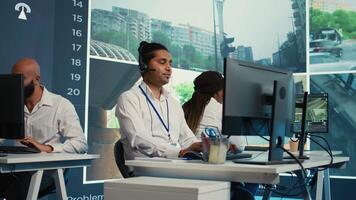 Indian employee communicating satellite map directions in observation room, monitoring traffic around the city via CCTV security system. Young man works with surveillance data. Camera B. video