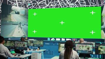 mensajero agencia operadores supervisión carga envío con un pantalla verde, trabajando en observación habitación. empleados dar direcciones a camión conductores atascado en tráfico, cctv sistema. cámara b. video