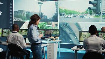 Team leader monitoring city traffic with her diverse team on a big screen, using real time surveillance footage to ensure public safety. Agency supervising CCTV security system. Camera B. video