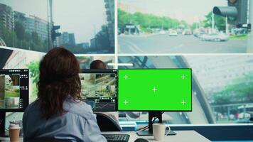 Agency employee works with greenscreen display and monitoring traffic, using city surveillance footage via satellite radar and CCTV system. Young woman following sensors. Camera B. video