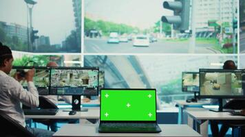 uma computador portátil corrida isolado brincar exibição dentro uma monitoramento sala, pessoas trabalhando com vigilância cenas a partir de cctv segurança máquinas fotográficas por aí a cidade. tela verde dentro uma governo agência. Câmera b. video