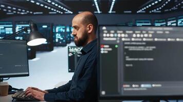 Software developer programming in high tech facility with server rows providing computing resources for different workloads. IT expert reviewing data center supercomputers video