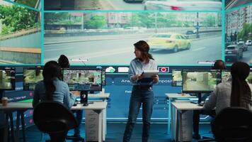 Portrait of woman supervisor overseeing the traffic surveillance monitoring activity in a observation room, CCTV satellite system. Diverse team of people handling license plate reading. Camera B. video