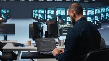 Computer scientist using laptop device to do programming in data center room housing servers . IT supervisor writing code on notebook to mend data storage facility racks doing computational operations video