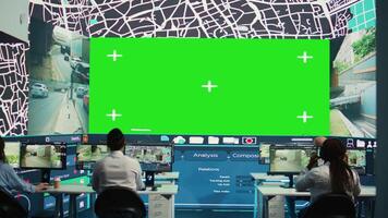 Envío agencia trabajadores examinar satélite mapa con enorme pantalla verde mostrar, supervisión parcelas y pedidos para clientela. empleados utilizando vigilancia cctv imágenes a obtener actualizaciones cámara b. video