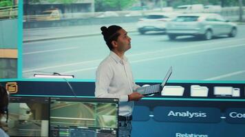 indisk man team ledare samordnar hans personal till observera urban övervakning antal fot genom de cCTV säkerhet systemet. regering byrå anställda övervakning trafik via satellit kameror. kamera b. video