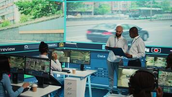 Diverse employees using CCTV surveillance system in monitoring traffic, tracking speed limits for public safety via satellite radar system. People operating on a big screen in control center. Camera B. video
