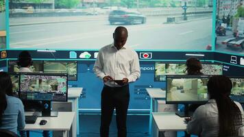 Agency supervisor working with his employees team in monitoring room, analyzing data on surveillance footage recorded by the CCTV satellite system spread around the city streets. Camera B. video