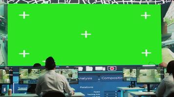 Remessa agência trabalhadores examinar satélite mapa com enorme tela verde mostrar, monitoramento parcelas e ordens para clientes. empregados usando vigilância cctv cenas para pegue atualizações. Câmera uma. video