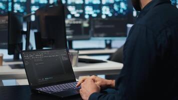 Computer scientist overseeing data center servers, typing code on laptop, troubleshooting rigs. Software professional doing maintenance on mainframes using notebook, close up shot video