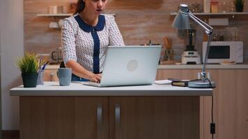 o negócio mulher trabalhando a partir de casa atrasado às noite escrevendo em computador portátil e bebendo café. ocupado focado empregado usando moderno tecnologia rede sem fio fazendo hora extra para trabalho lendo digitando, procurando video