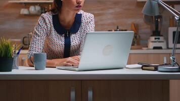 pensiero a Il prossimo progetto mentre Lavorando a distanza a partire dal casa, lettura il compiti utilizzando il computer portatile seduta nel il cucina. occupato focalizzata dipendente utilizzando moderno tecnologia Rete senza fili fare col tempo per lavoro digitando scrivere, ricerca video