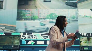 Indian supervisor gather intelligence on cargo delivery logistics by following the route through street traffic via satellite map. Manager works with her team in control center. Camera B. video