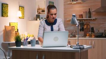 emocionado mujer sensación extático leyendo genial en línea Noticias en ordenador portátil trabajando desde hogar cocina. contento empleado utilizando moderno tecnología red inalámbrico haciendo tiempo extraordinario estudiando escribiendo, buscando video