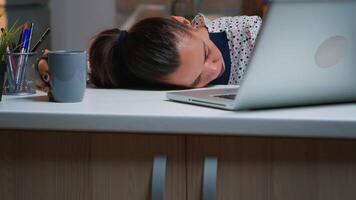 uitgeput overbelasten bedrijf vrouw vallend in slaap Aan bureau met Open laptop toezicht houden op terwijl werken van huis. bezig werknemer gebruik makend van modern technologie netwerk draadloze aan het doen na een tijdje slapen Aan tafel. video