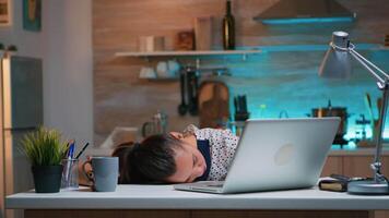 sobrecargado de trabajo cansado mujer trabajando desde hogar tala dormido en escritorio en frente de ordenador portátil. ocupado enfocado empleado utilizando moderno tecnología red inalámbrico haciendo tiempo extraordinario clausura ojos y dormido en mesa. video