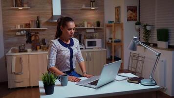 esausto a distanza dipendente streching mentre Lavorando su un' Scadenza in ritardo a notte. occupato focalizzata libero professionista utilizzando moderno tecnologia Rete senza fili fare col tempo per lavoro lettura scrivere, ricerca video